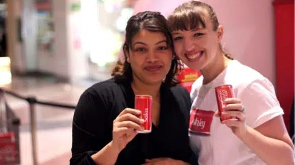 Two smiling women holding personalised Share a Coke cans printed with their names